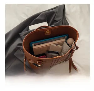 Spacious interior of brown leather tote bag showing storage for tablet, books, and phone