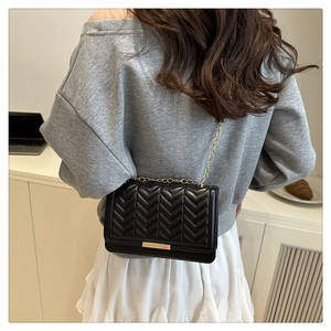 Détail du sac bandoulière noir en similicuir avec chaîne dorée et matelassage en V