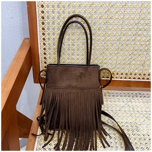 Detail of dark brown suede tassel bucket bag on a vintage rattan chair with long fringes