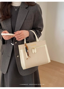 Detail der creme-gewebten Handtasche mit Ledergriffen und bunter Perlenanhänger-Dekoration