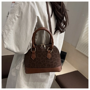 Detailed side view of a brown leopard print shell bag with faux leather strap and handle