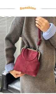 Detail view of burgundy vintage kiss-lock bag with white stitching and suede texture