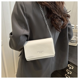 Détail d'un sac bandoulière blanc cassé avec chaîne argentée porté par un mannequin