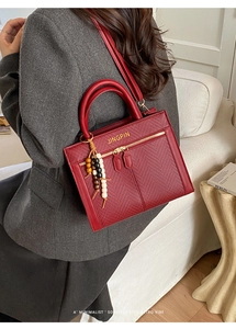 Detail der roten Leder Boston Tasche mit Metalllogo, Perlenanhänger und Goldbeschlägen