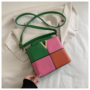Detail of color-block crossbody bag with pebbled leather and golden V-shaped metal buckle