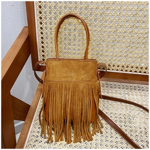 Detail of bohemian brown suede bucket bag featuring long fringe and round handles