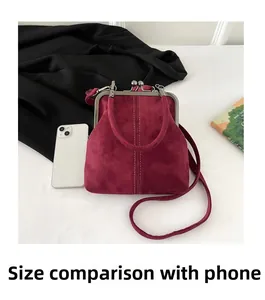 Detail of burgundy suede clasp handbag next to a smartphone showing compact size