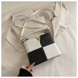 Detail of chessboard pattern crossbody bag with golden V-clasp and litchi texture leather