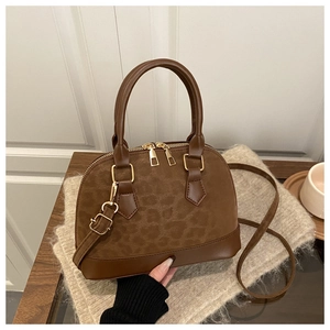 Close-up of brown leopard print shell bag on beige knitwear with gold zippers