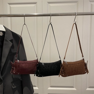 Three leopard print bow hobo bags in burgundy, black and camel on white wooden door