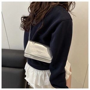 Sac bandoulière argenté brillant porté par un mannequin, montrant la taille réelle