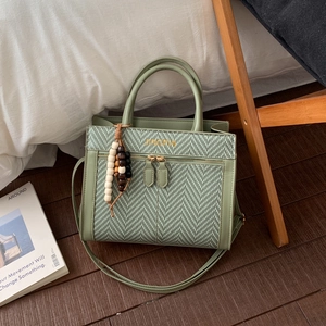 Detailed shot of sage green woven crossbody bag with JINGPIN logo and beaded tassel