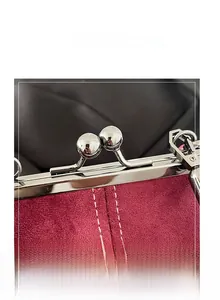 Detail of burgundy frosted bag with silver metal kiss-lock clasp and white stitching