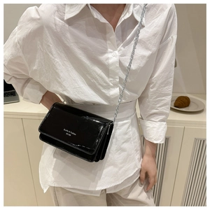 Mannequin portant un sac à bandoulière en cuir verni noir avec chaîne argentée