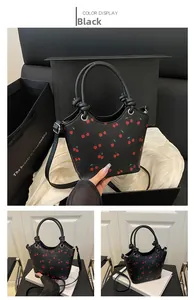 Detail shot of black cherry print bucket bag with round handles and adjustable strap
