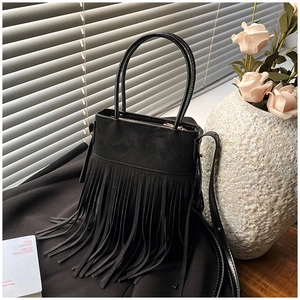 Close-up of black bohemian fringe bucket bag with soft suede texture and long tassels
