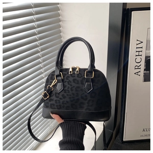 Detail of elegant black leopard print shell bag with gold hardware and leather handle