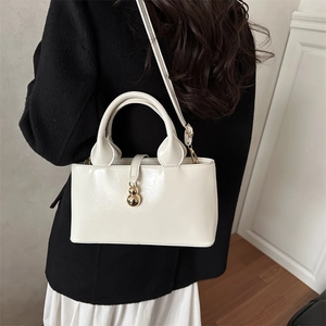 Detailed side view of a white PU leather tote bag with a golden gourd charm detail