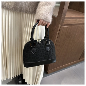 Close-up of leopard print shell bag with golden zippers and black faux leather details