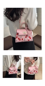 Detail of pink cherry print crossbody bag showing gold twist lock and rounded top handle