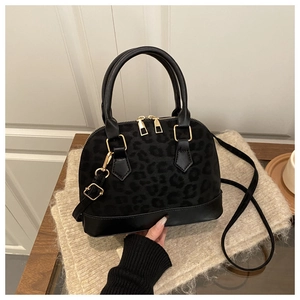 Detail of black leopard texture handbag with golden hardware on soft fabric