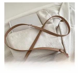 Dettaglio della tracolla regolabile in pelle beige con fibbia dorata e cuciture sottili