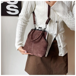 Detailed close-up of brown suede doctor bag with white stitching and metal clasp