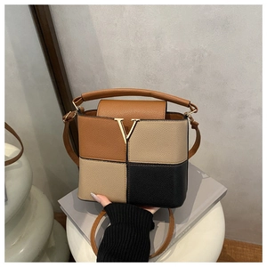Close-up of color-block square bag with V-shaped metal logo and pebbled leather texture
