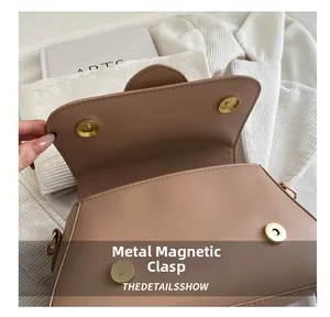Dettaglio della chiusura magnetica dorata di una borsa a tracolla in pelle marrone