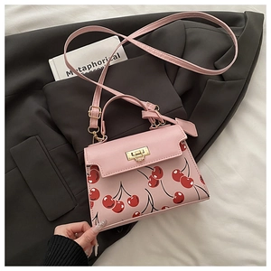 Close-up of pink cherry print handbag with golden metal clasp on a grey blazer