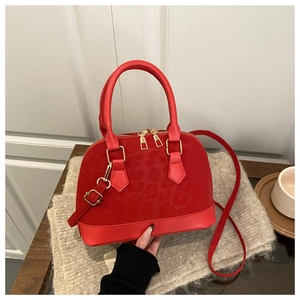 Detail view of red shell handbag featuring leopard print panel and gold hardware details