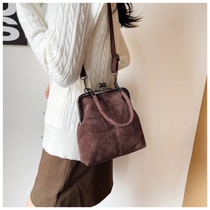Detail of brown suede kiss-lock bag showing retro metal clasp and stitching
