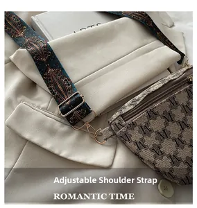 Detailed close-up of retro monogram pattern and wide printed strap on crossbody bag