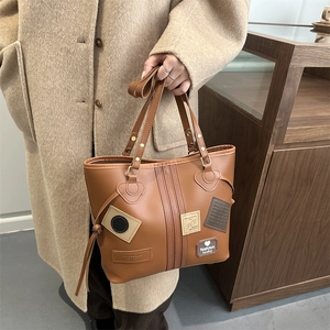 Detail of vintage brown tote bag with decorative fashion lucky heart and HJ patches