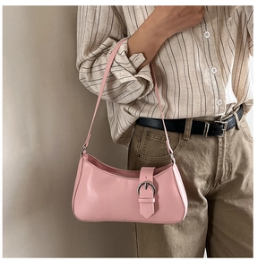 Detail of pink baguette bag with decorative silver buckle on a shoulder strap
