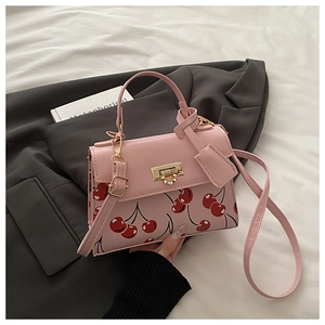 Close-up of pink cherry print PU leather bag with golden clasp and adjustable strap