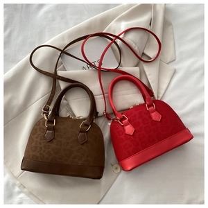 Detail view of stylish leopard print shell handbags in brown and red with metal chains