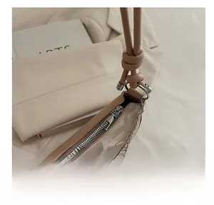 Detail view of smooth silver zipper and F-pattern on beige PU leather underarm bag