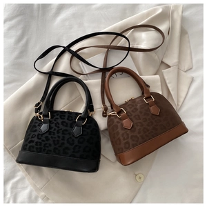Detail view of two leopard print shell bags in brown and black on a white blazer