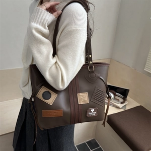 Detailed view of vintage brown leather tote bag with retro patches and side drawstring