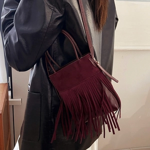 Retro Bohemian Burgundy Suede Bucket Bag with Tassels shown on model in black coat