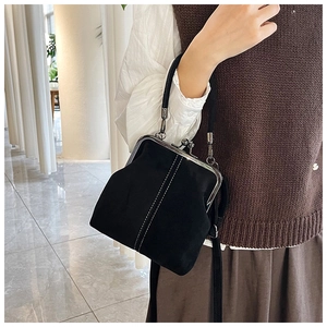Detail of black retro kiss-lock bag with white stitching and silver metal buckle
