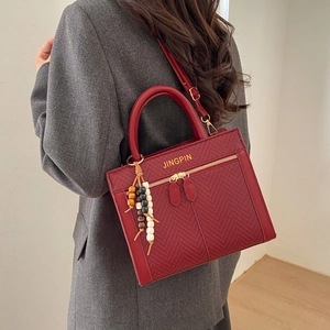 Chic red woven texture handbag with crossbody strap and wooden bead pendant accessory