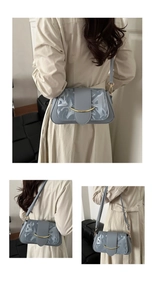 Dettaglio della borsa in pelle blu-grigio con fibbia dorata a mezzaluna e texture