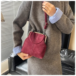 Detail view of burgundy faux suede vintage crossbody bag with metal clasp and white stitching