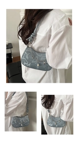 Detail of light blue crescent underarm bag with monogram fabric and pearl chain charms