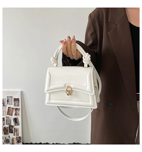 Detail of white PU leather handbag featuring a gold ring clasp and twisted handle design