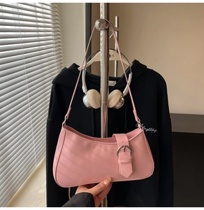 Detailed view of a light pink French baguette bag with a large metallic belt buckle