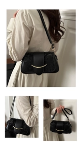 Dettaglio del tessuto jacquard nero e fibbia dorata curva sulla piccola borsa a tracolla