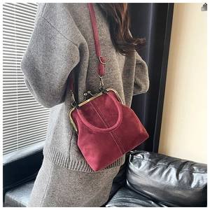Detail of vintage burgundy kiss-lock handbag with matte suede texture and bronze metal clasp